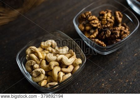 Almond, Cachew And Walnut In A Small Plates Which Standing On A Black Table. Nuts Is A Healthy Veget