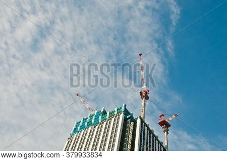Underconstruction Building In Progress With Many Construction Cranes And Bright Sunny Blue Sky With 