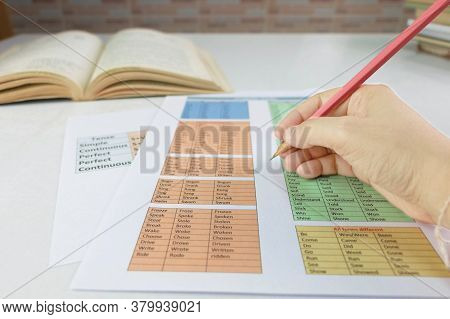 Hand Holding Pencil Over English Grammar Sheet On Table In Classroom