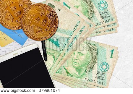 1 Brazilian Real Bills And Golden Bitcoins With Smartphone And Credit Cards. Cryptocurrency Investme