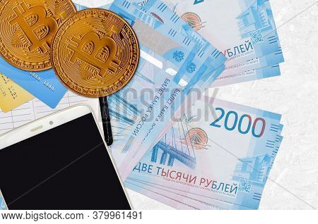 2000 Russian Rubles Bills And Golden Bitcoins With Smartphone And Credit Cards. Cryptocurrency Inves