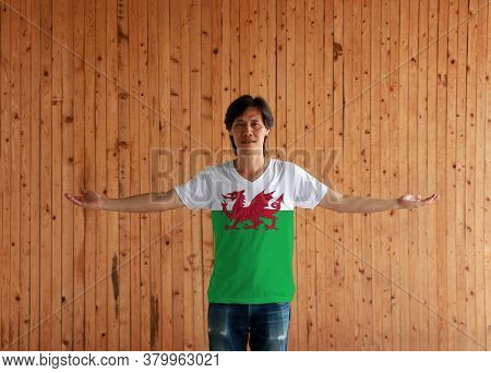 Man Wearing Wales Flag Color Shirt And Standing With Arms Wide Open On The Wooden Wall Background, R