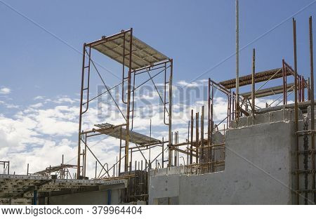 The Steel Scaffolding With Brown Rust Standing On The Top Floor Of The Building Under White Fluffy C