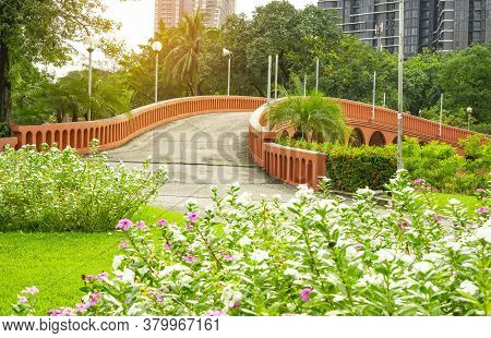 Orange Concrete Arch Curve Brige And Lake In A Beautiful Garden, Fresh Pink And White West Indian Pe