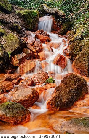 Detail Of The Mineral Springs. Cascade On Stream Of Mineral Water With Ferric Sediment On Green Moss