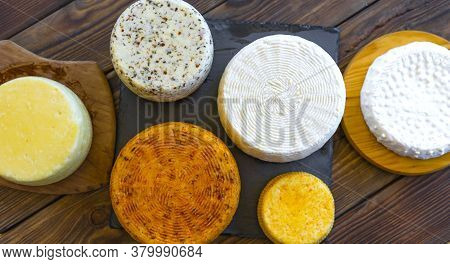 Cheese Heads With Cheeses Of Different Kinds. Assortment Of Different Cheese Types On Wooden Backgro