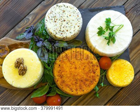 Cheese Heads With Cheeses Of Different Kinds. Assortment Of Different Cheese Types On An Old Wooden 