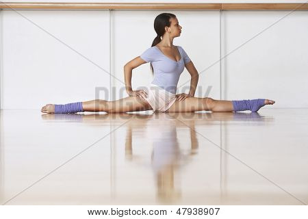 Tutta la lunghezza della giovane ballerina sul pavimento di legno in posizione di Spalato a rehearsal