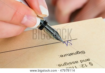 una donna firma un contratto o un testamento con una penna stilografica.