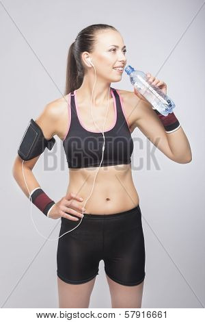 Fit Woman Training While Dringking Form Small Bottle - Isolated Over Gray Background