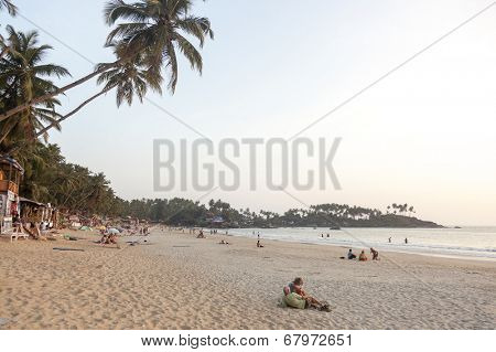 Palolem, India - January 4, 2013: Palolem beach in the south of Goa in India with coconut palm trees in the back. There mostly western tourists on the sand and coconut huts and restaurants.