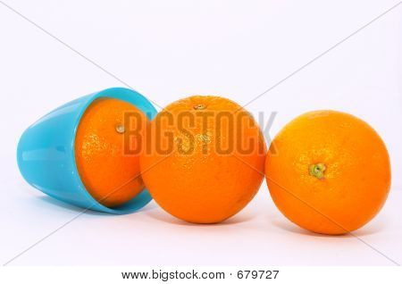 drei Orangen mit hell blauer Becher