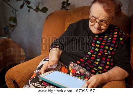 Elderly lady sitting in an chair using a tablet
