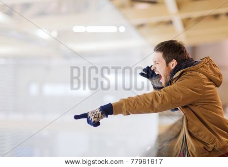 people, sport, emotions and leisure concept - happy friends watching hockey game or figure skating performance, pointing finger and shouting on skating rink