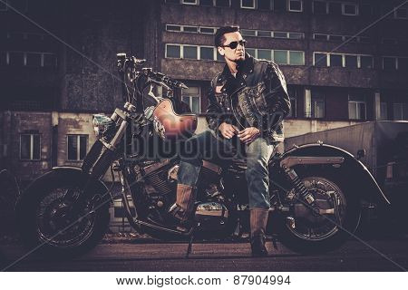 Biker and his bobber style motorcycle on a city streets 