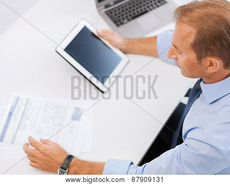 business, office, school and education concept - businessman with tablet pc and papers in office