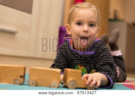 Cheeky Little Girl Is Playing With A Wooden Toy