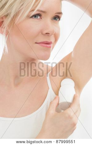 Closeup of young woman applying deodorant to her armpit 