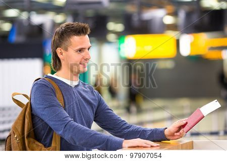 Beautiful man with passports and boarding passes at the front desk at airport