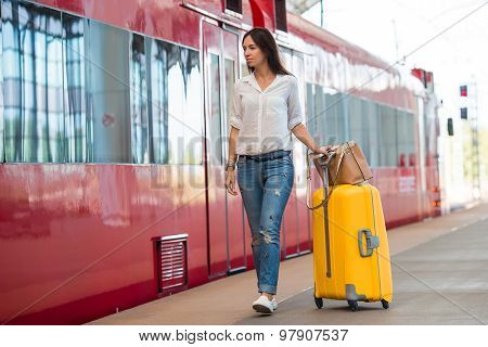 Young happy woman with luggage at a train station