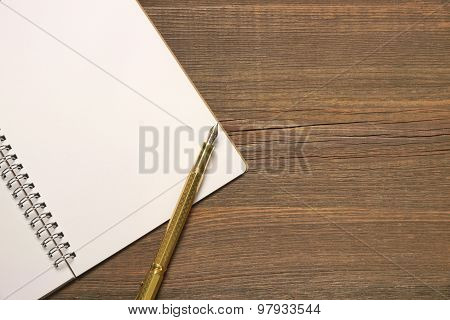 Open Spiral Bound Notebook With White Pages And Gold Pen.