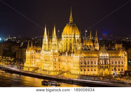 Budapest parliament building at night with dark sky and reflection in Danube river.