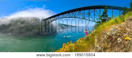 Woman meditating on seashore by the bridge. Deception Pass Bridge. Anacortes. Whidbey Island. Strait of Juan de Fuca. Puget Sound. WA. USA.