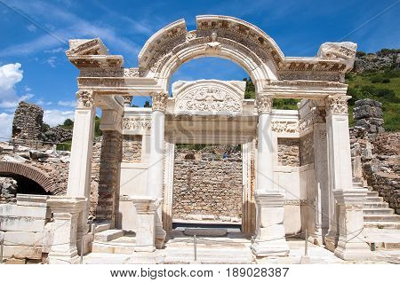 Izmir, Turkey - May 10, 2017: Hadrian's temple ruins with tourists walking around in anceint city of Ephesus on sunny day