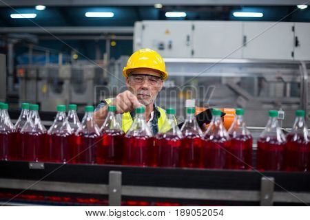 Male factory worker monitoring cold drink bottles at drinks production factory