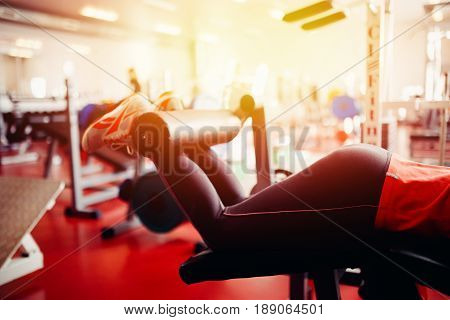 girl in the gym makes an exercise on her feet on the simulator.  hign contrast and monochrome color tone