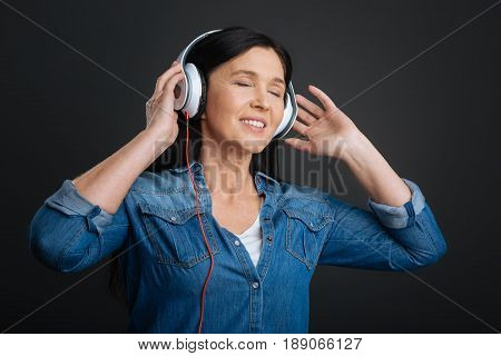 Expressing oneself through hobby. Graceful pretty emotional woman having the headphones on and enjoying amazing song while closing her eyes