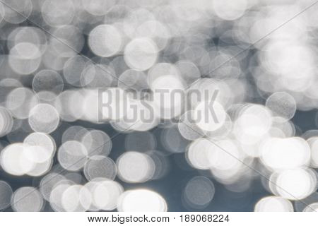 Water bokeh background. Defocused water surface with waves glittering in the sun.