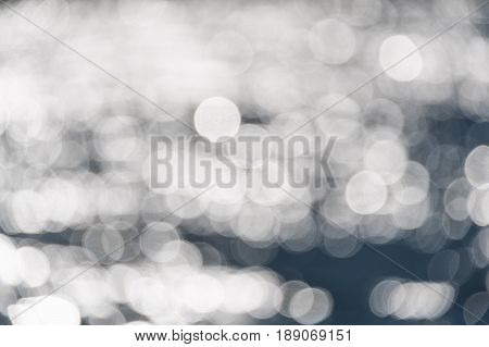 Water bokeh background. Defocused water surface with waves glittering in the sun.