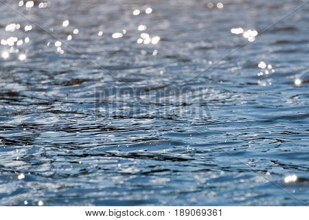 Water with bokeh background. Water surface with waves glittering in the sun.