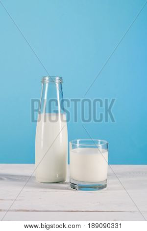 Close Up Of Milk In Glass And Bottle On Tabletop At Blue Background