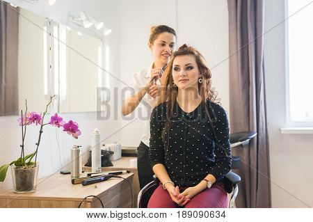 working day inside the beauty salon. Hairdresser makes hair styling.