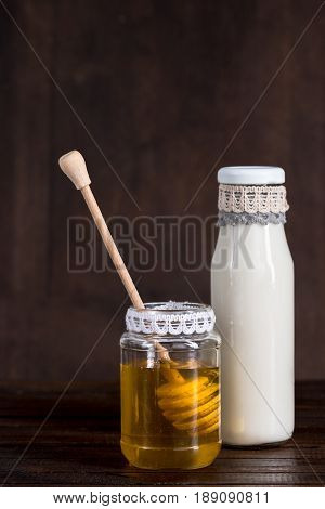 Glass Bottle Of Milk With Honey In Jar On Wooden Background