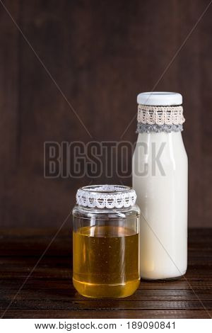 Glass Bottle Of Milk With Honey In Jar On Wooden Background