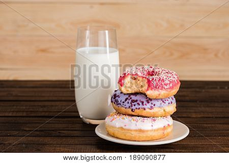Close Up Of Glass Of Milk With Donuts On Plate On Wooden Background