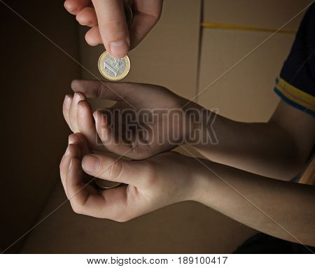 Female hand putting coin into hands of poor child, closeup