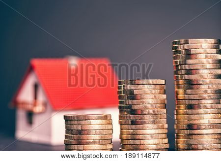Rising stacks of coins and a house in the background