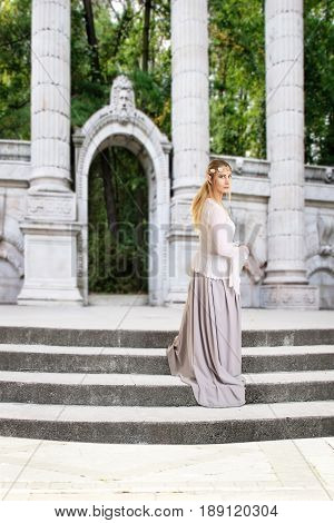 female elf on stone stairs with entrance to forest