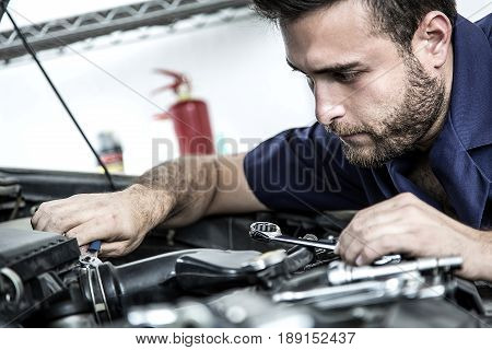 Car Mechanic Man At The Garage Fixing The Engine
