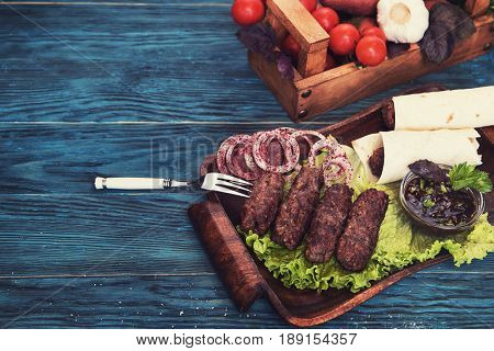 Grilled lula kebab - meat dish, with vegetable on a blue wooden background