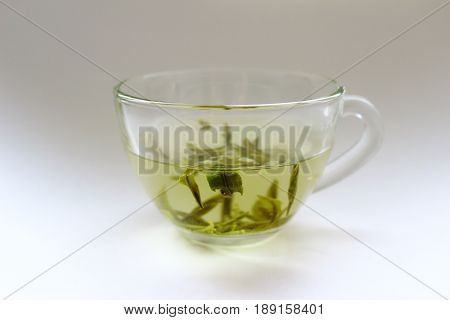 A transparent cup of green tea on a white background