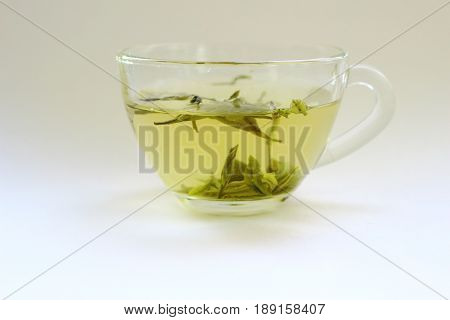 A transparent cup of green tea on a white background