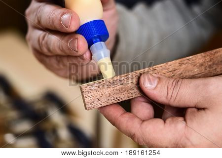 Carpenter applying glue on wooden detail closeup