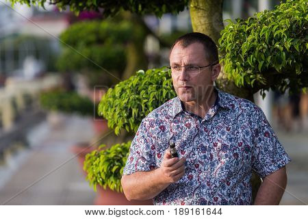 Adult senior man vaping electronic cigarette outdoor.