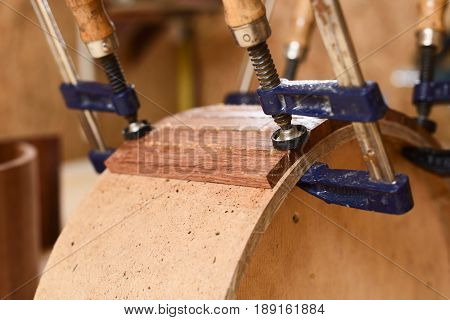 Part of handmade wooden drum held in clamp closeup