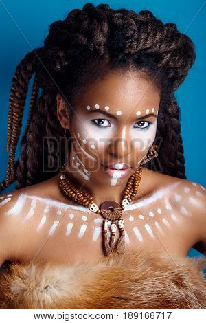 African style . Attractive young woman in ethnic jewelry . close up portrait of a woman with a painted face. Creative makeup and bright style.
